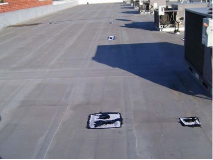 Flat commercial rooftop with HVAC units and several rectangular patches.