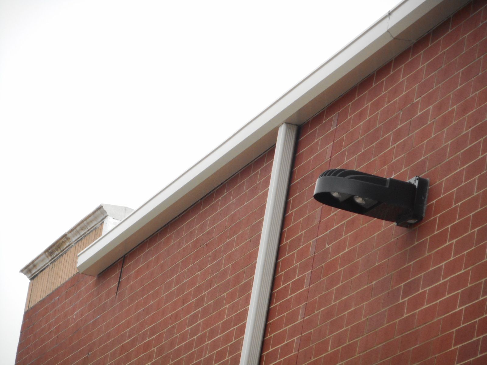Red brick building exterior with white trim and a black security light.