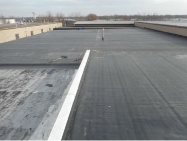 Flat, black commercial roof with white edging and vents.