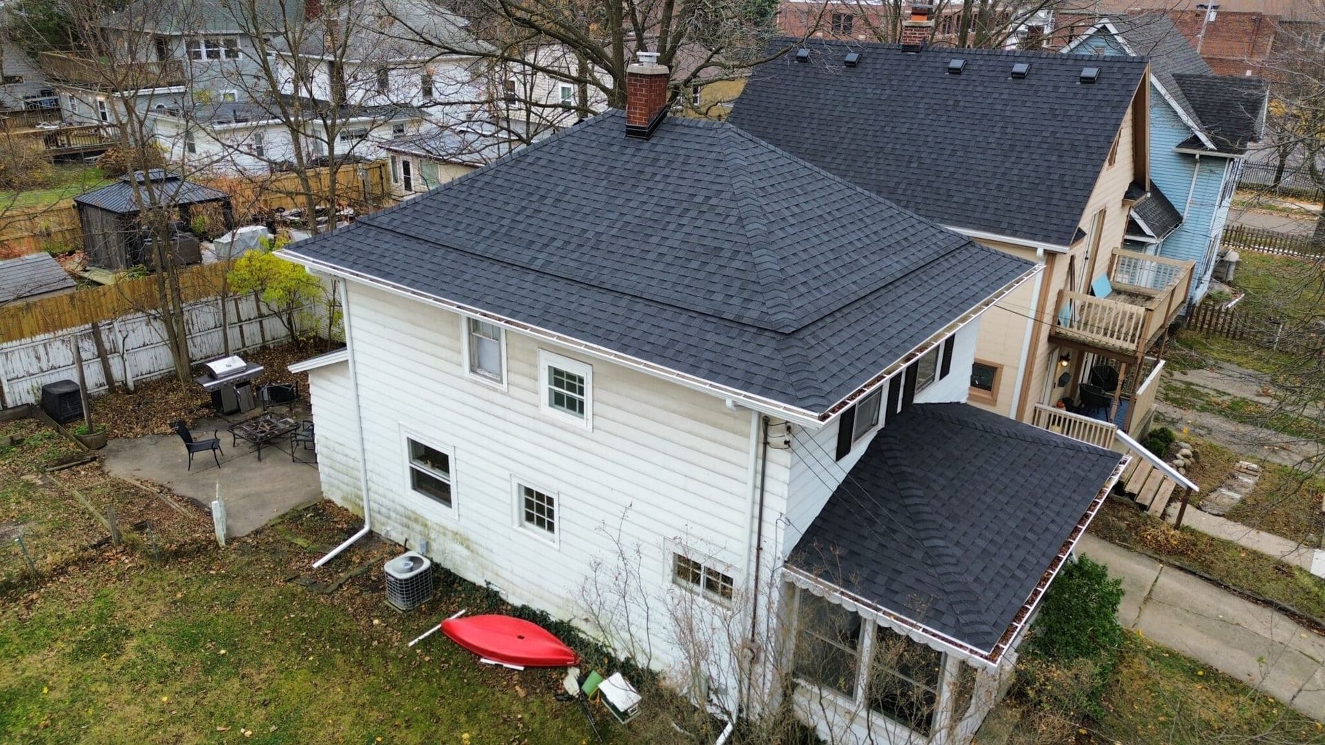 White two-story house with dark gray roof, red kayak, and screen porch.