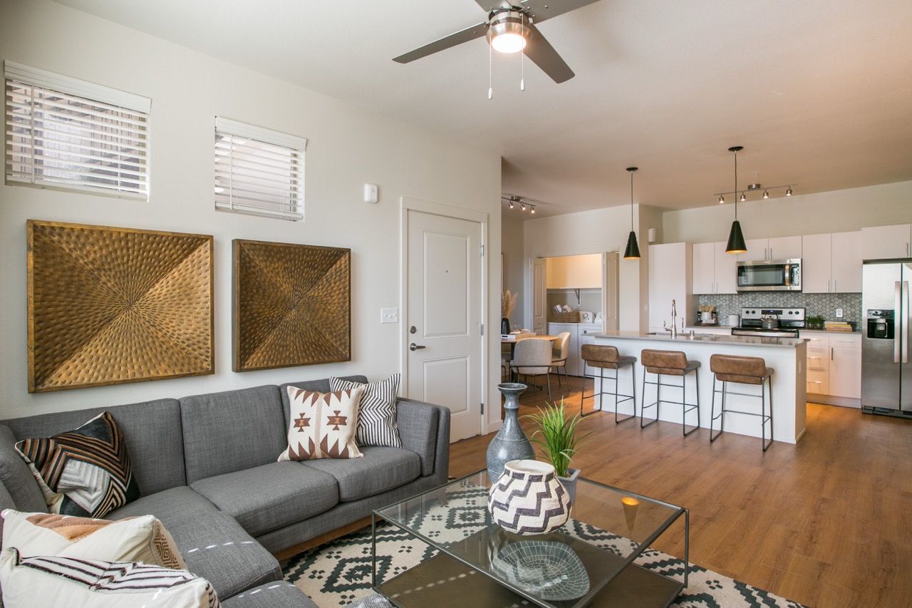 Open-concept living room with a gray sectional sofa and a modern kitchen island.