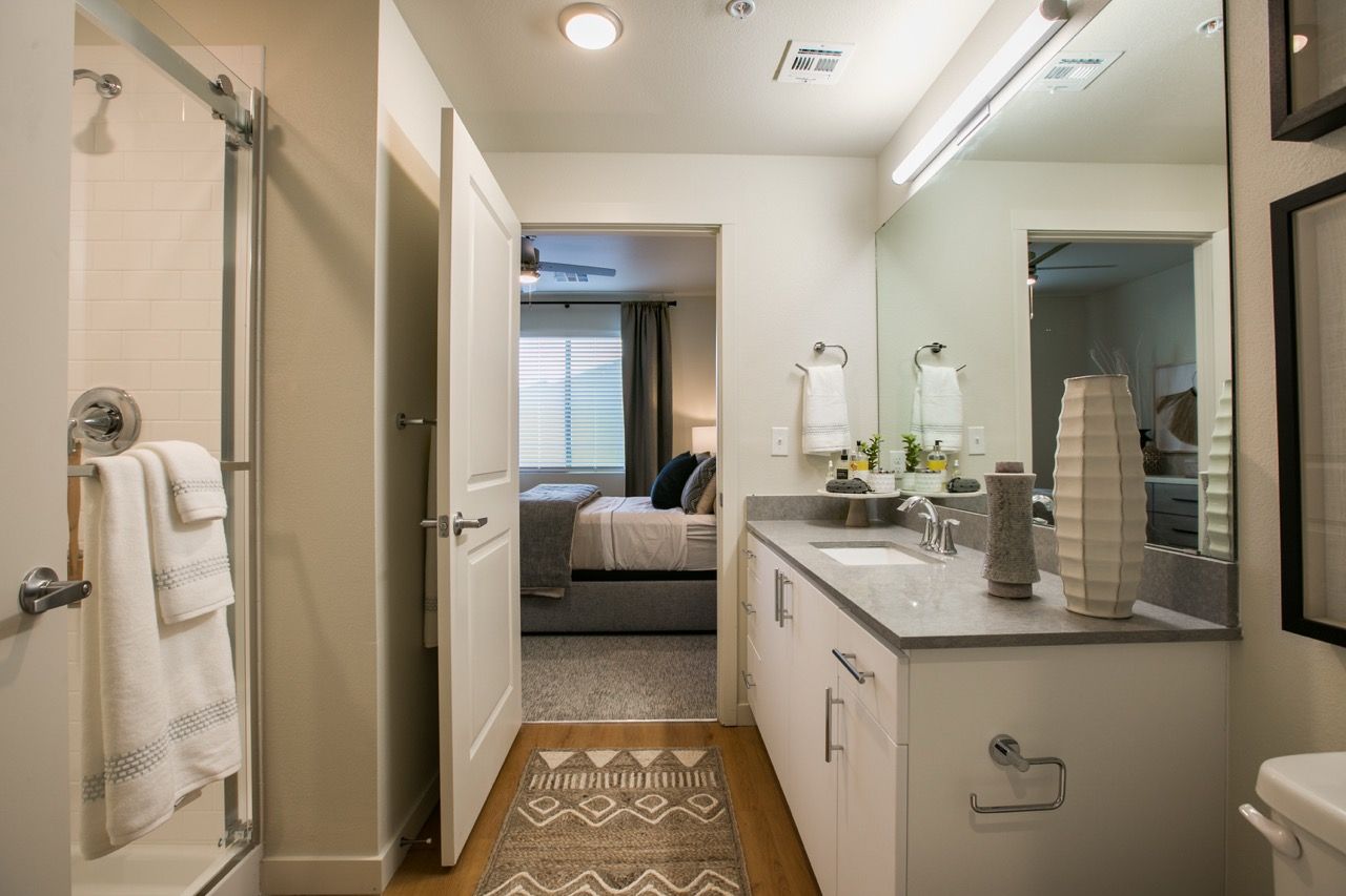 Apartment bathroom with double-sink vanity, large mirror, and glass shower.