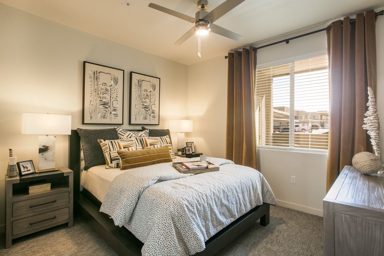 Bright modern bedroom with a large window, bed, two nightstands, and abstract art above the headboard.