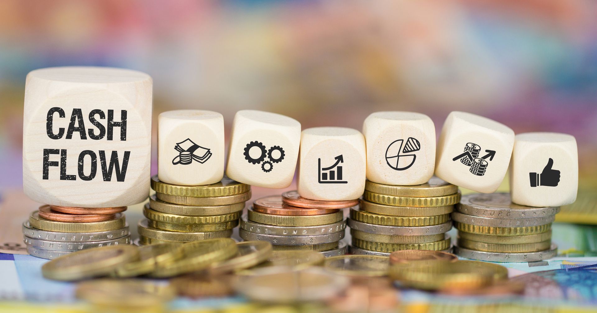 Showing wooden blocks with financial icons and text CASH FLOW stacked on piles of coins. Showing wooden blocks with financial icons and text CASH FLOW stacked on piles of coins.