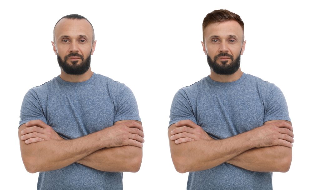 Two men, both with arms crossed, in blue shirts. The left man has dark hair, the right has red hair.