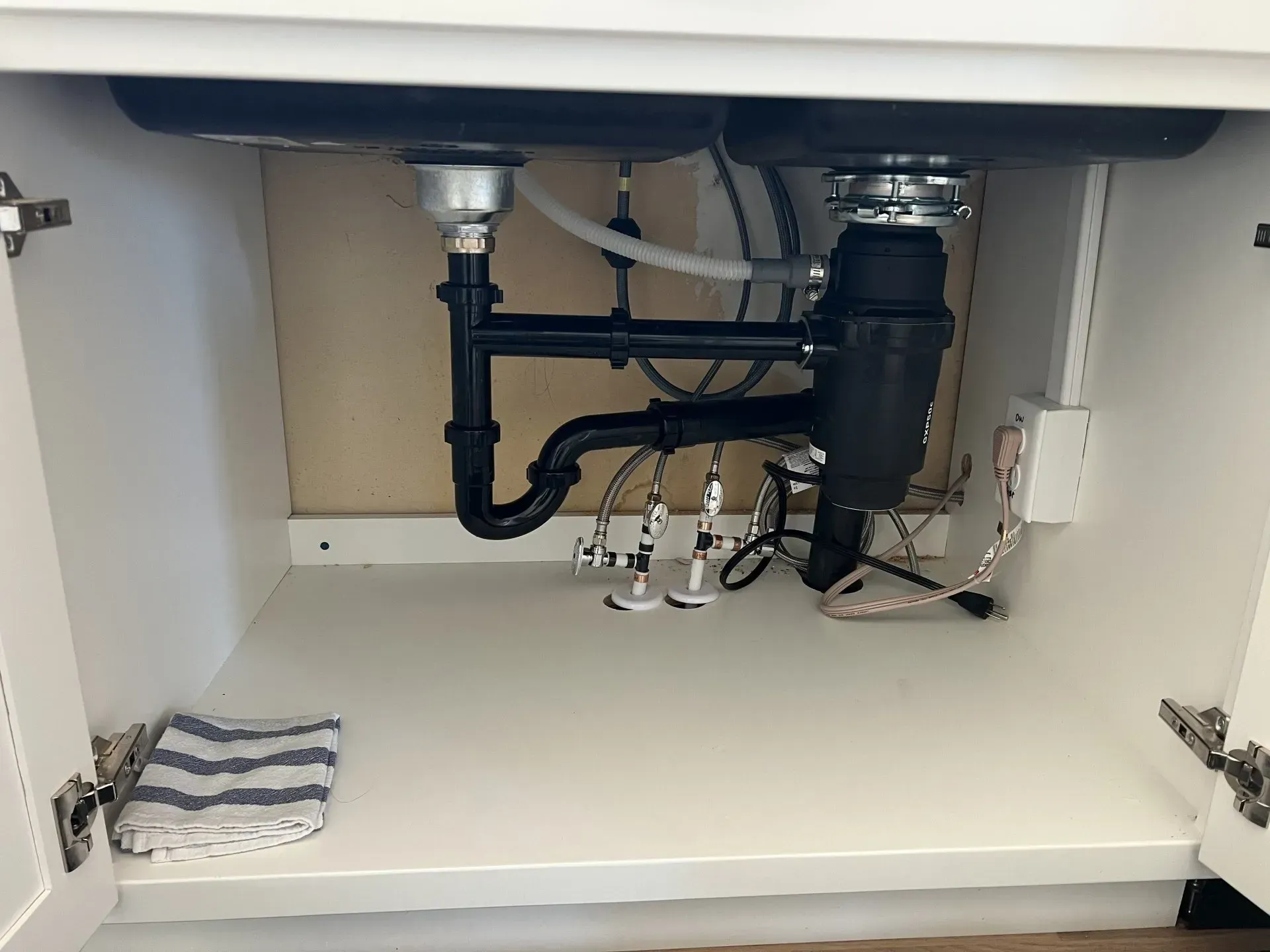 A kitchen sink with a garbage disposal underneath it in a cabinet.