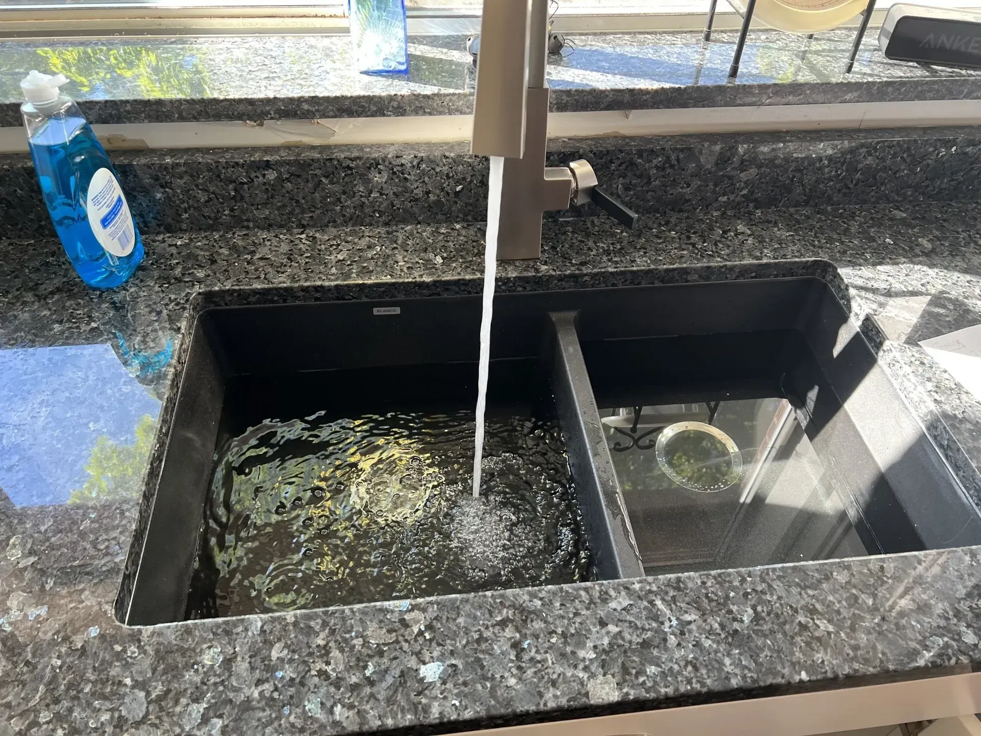 A kitchen sink with a bottle of dish soap on the counter.