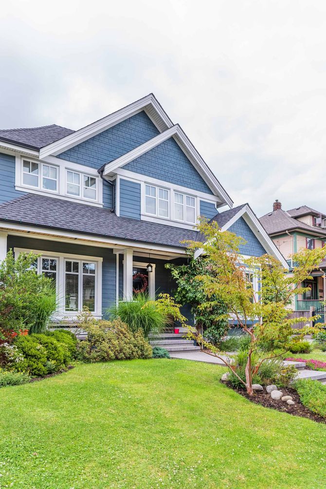 A large blue house with a lush green lawn in front of it.