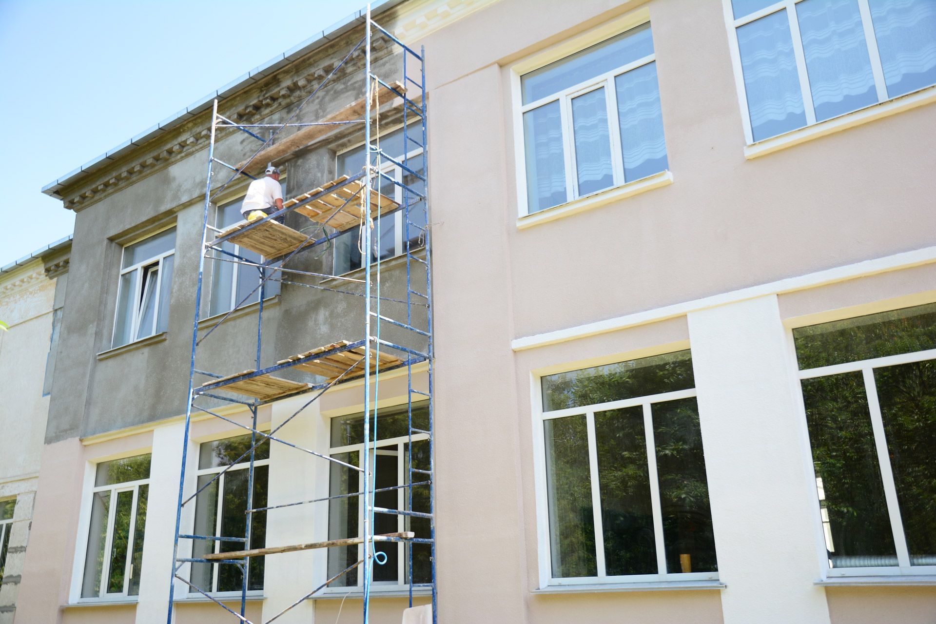 A man is standing on a scaffolding on the side of a building.