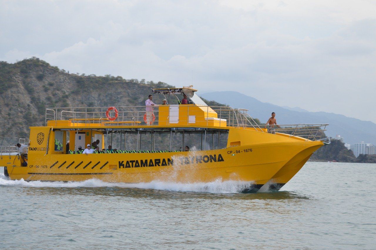 Catamarán amarillo navegando en el agua con fondo de montañas; 