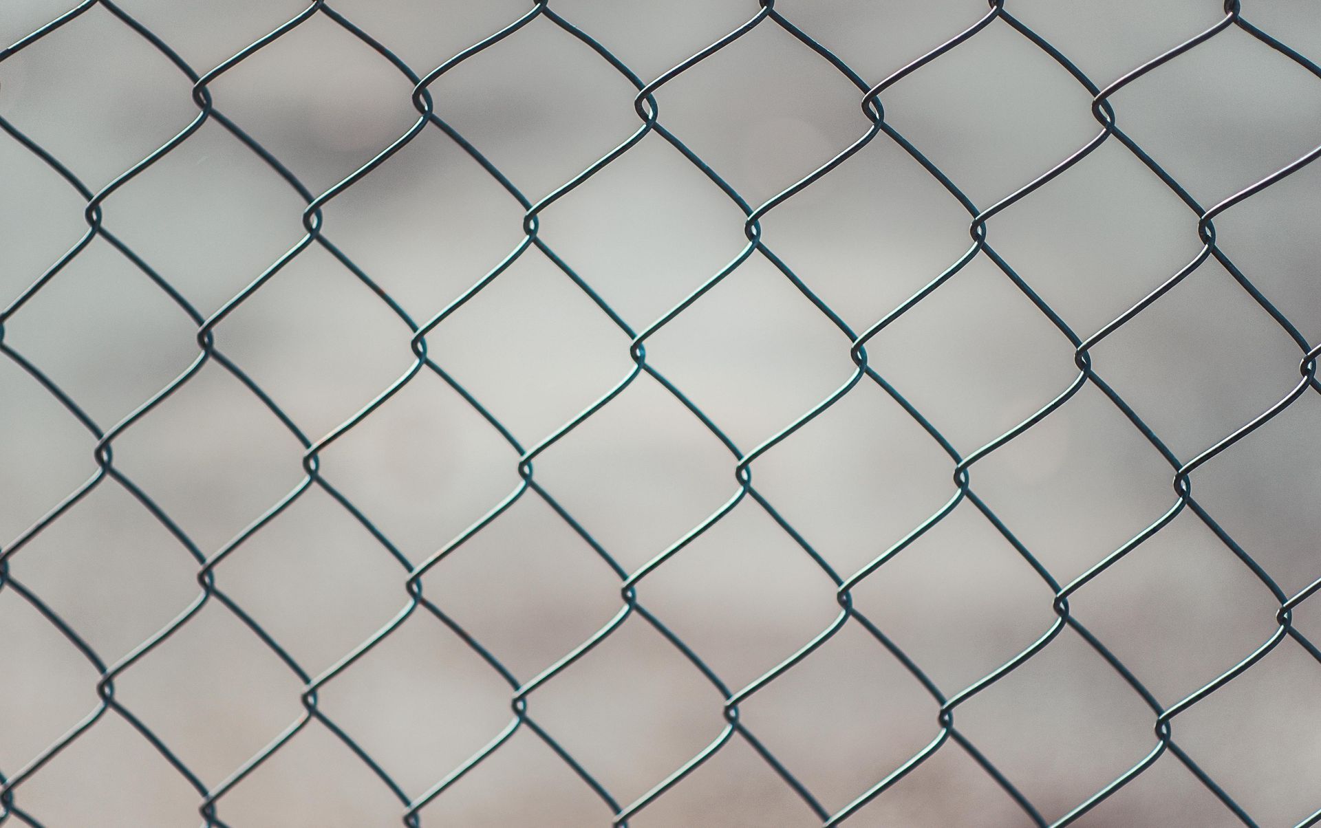 A close up of a chain link fence with a blurred background.