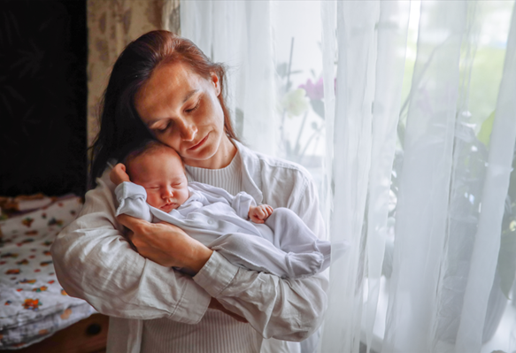 Woman holding a baby, representing postpartum care given by a gynecology physician in Waukee IA.