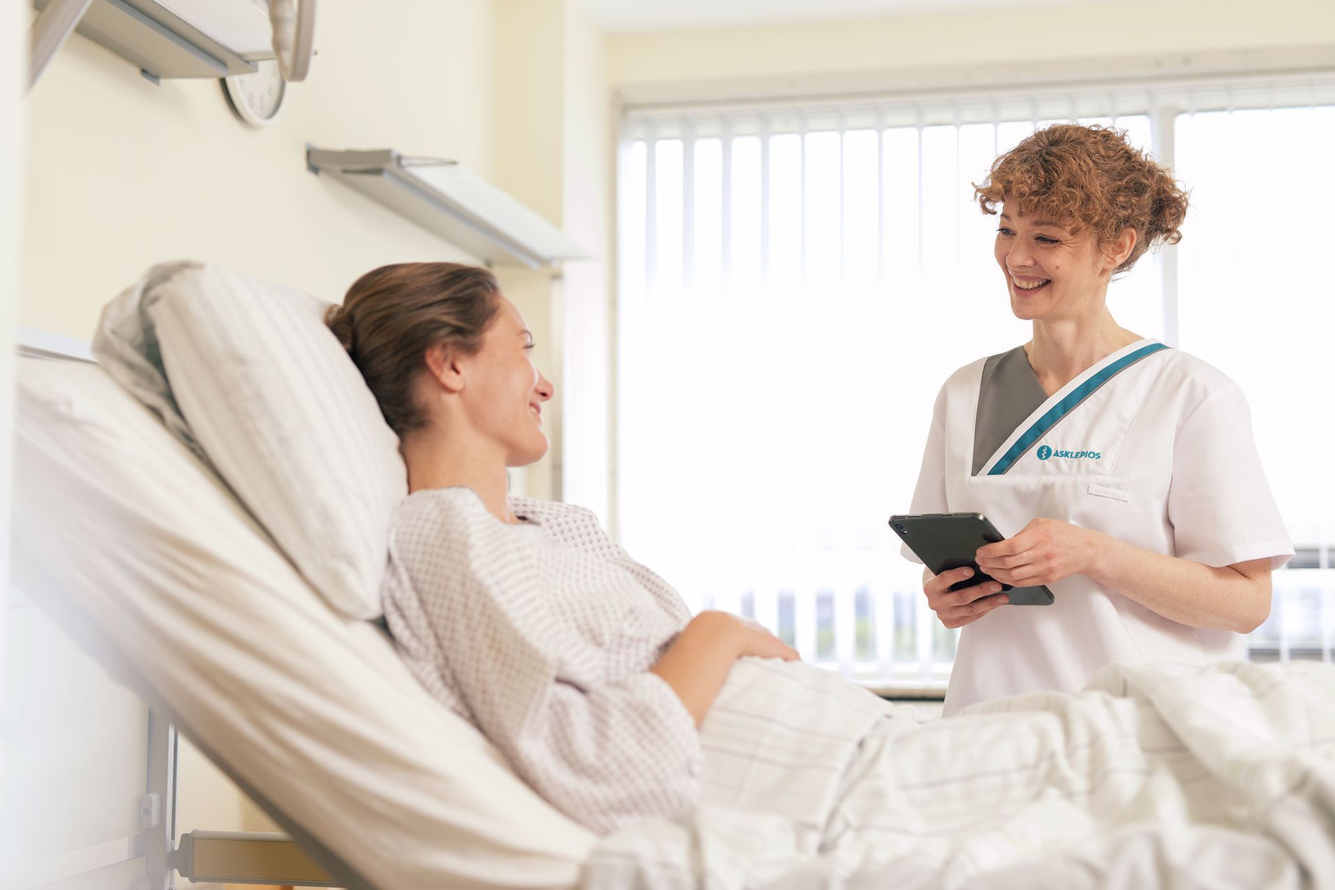 Aksklepios Pflegekraft am Bett eines Patienten in einem Krankenhaus