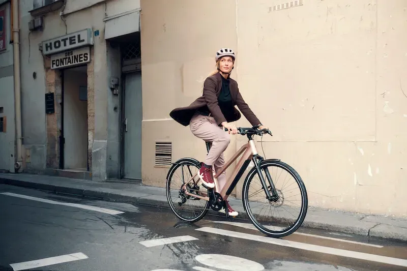 Eine Frau fährt mit dem Fahrrad eine Stadtstraße entlang.