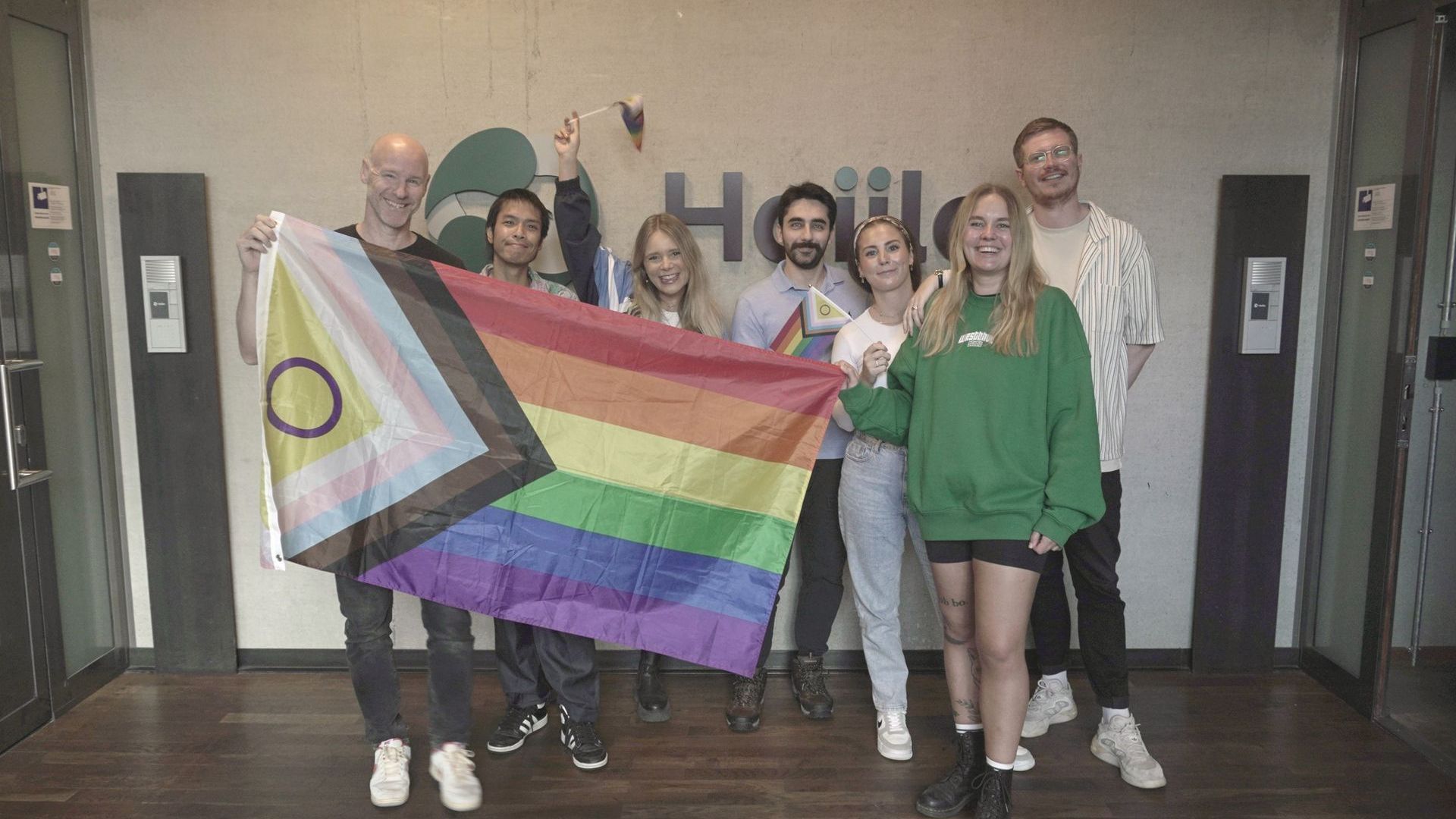 A group of people are holding a rainbow flag