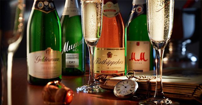 Several bottles of champagne are sitting on a table next to a pocket watch.
