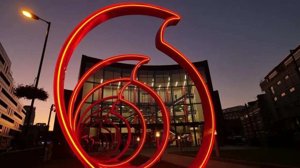 A large red sculpture is lit up in front of a building