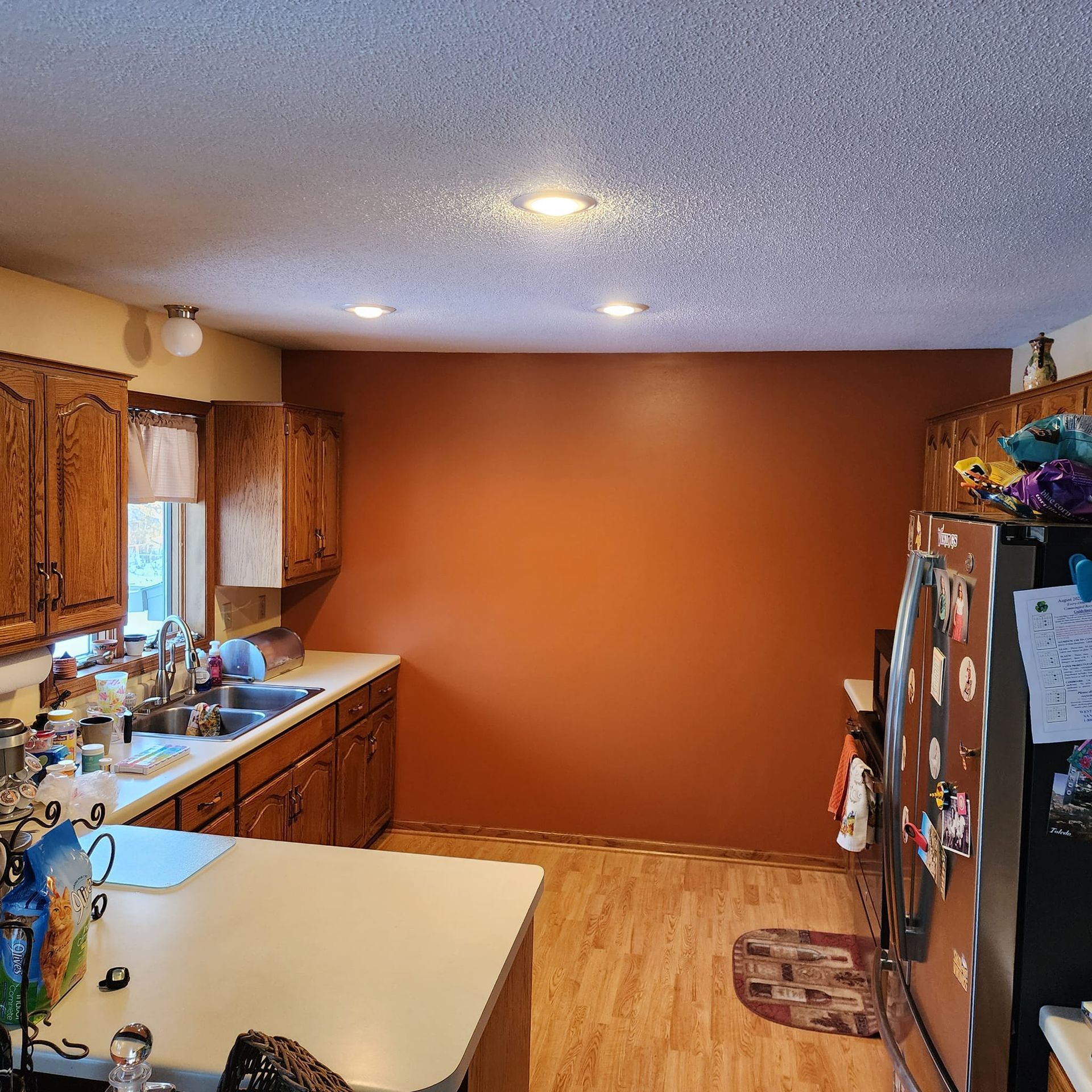 Kitchen with wood cabinets, a brown wall, and a stainless steel refrigerator.