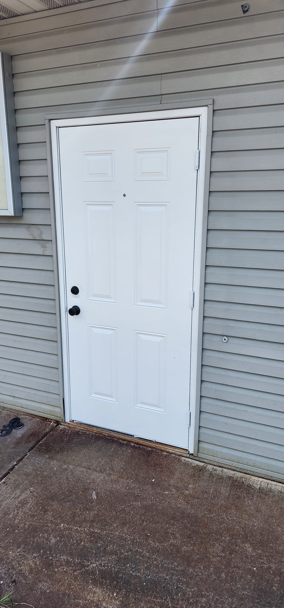 White door on a gray building with dark hardware.