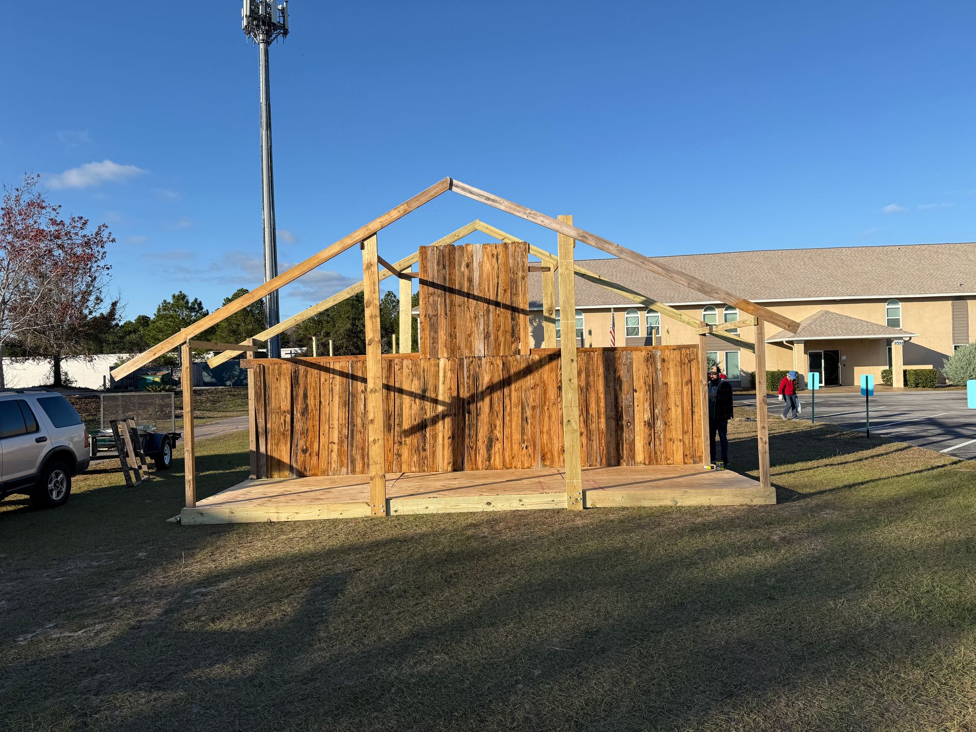 Wooden structure being built outdoors; includes a platform and central wall.