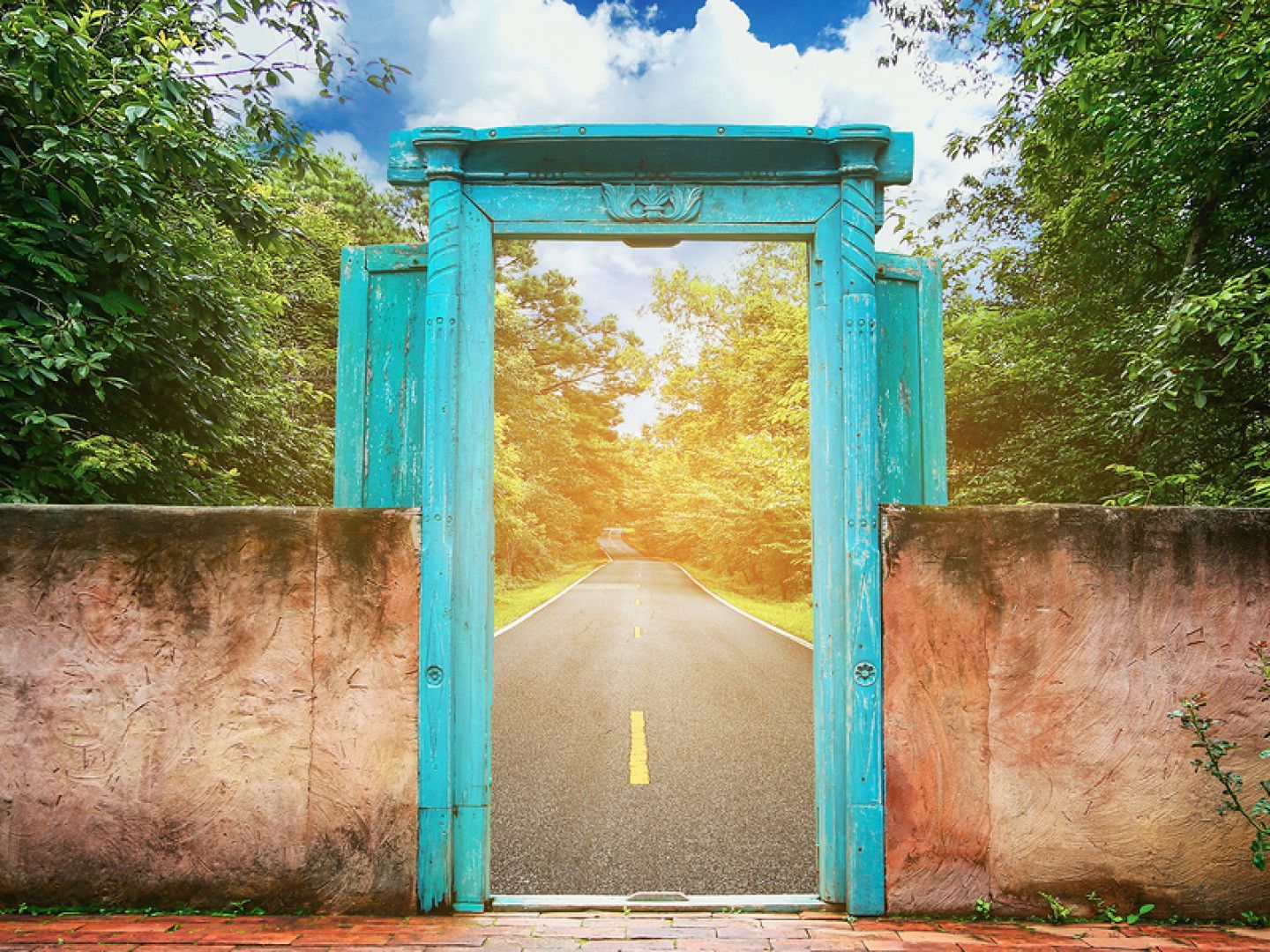 Turquoise doorway frames a road leading through trees toward bright sunlight.