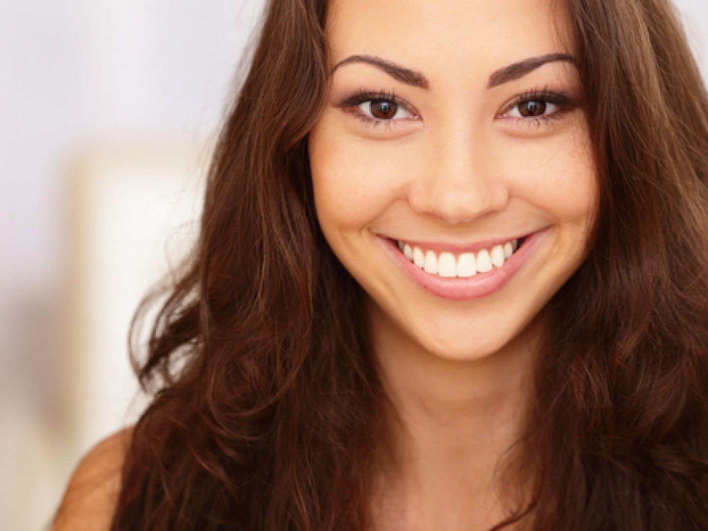 Smiling woman with brown hair, brown eyes, and white teeth.