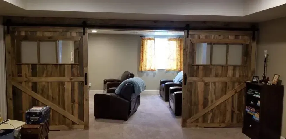 Barn doors open to a living room with seating and a window.
