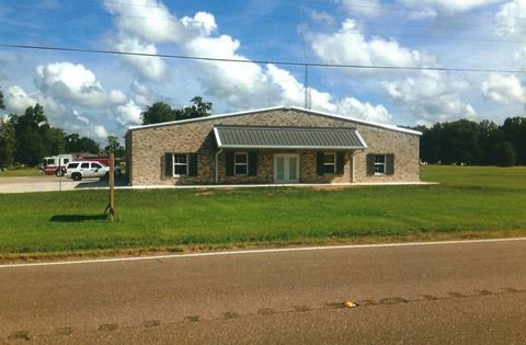 Single-story brick building with a gray roof, large lawn, and a white truck parked beside it.