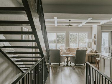 A modern staircase leading to a living room with a sofa, chairs, and a coffee table.