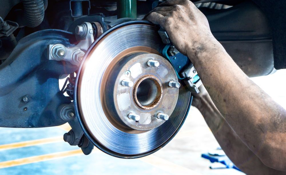 A Man is Fixing a Brake Disc on a Car — Cartech Australia in Wodonga, VIC