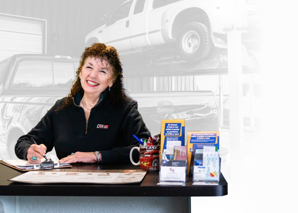 A woman is sitting at a desk in front of a truck. | D&W Auto Repair