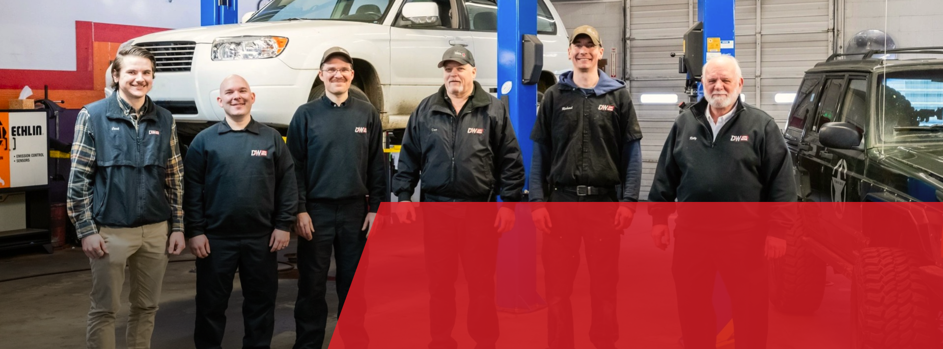 A group of men are standing in front of a truck in a garage. | D&W Auto Repair