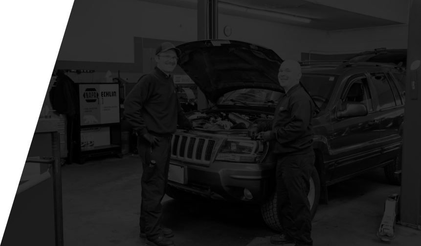 Two men are working on a jeep in a garage with the hood open. | D&W Auto Repair