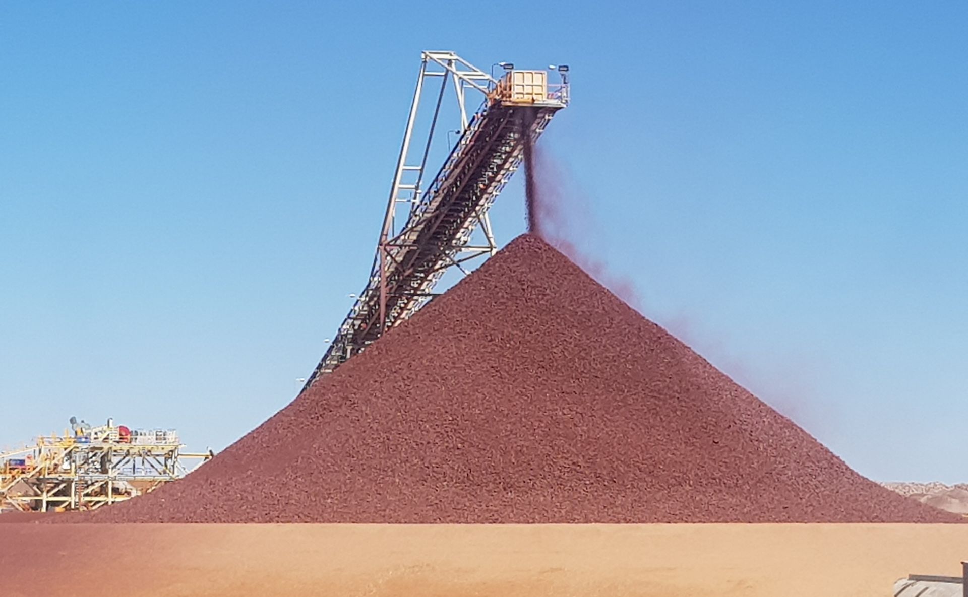Aerial view of a sand processing site with machinery, conveyor belts, and large piles of sand.