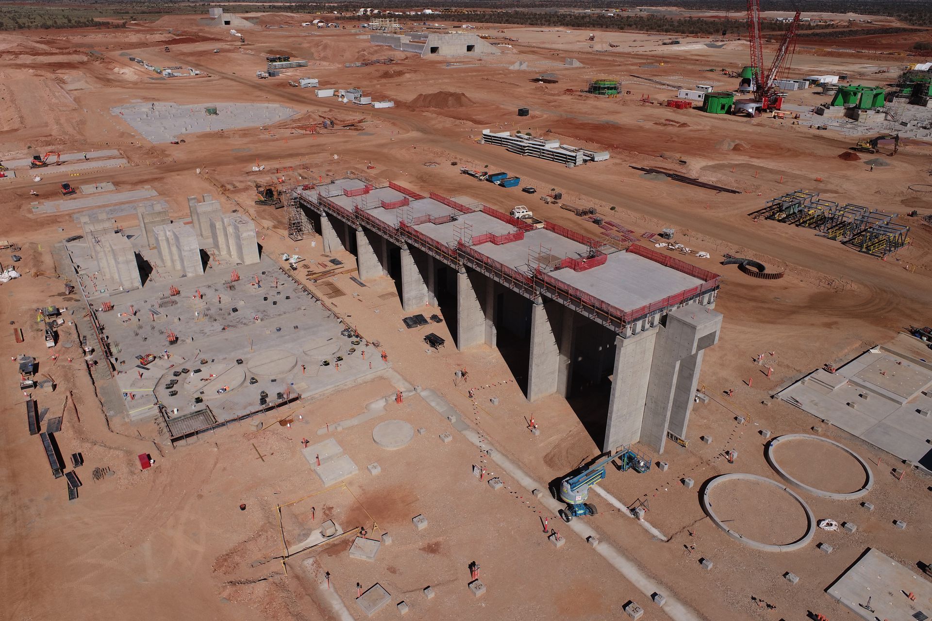 Red dump truck being loaded with material at a construction site in a desert setting.
