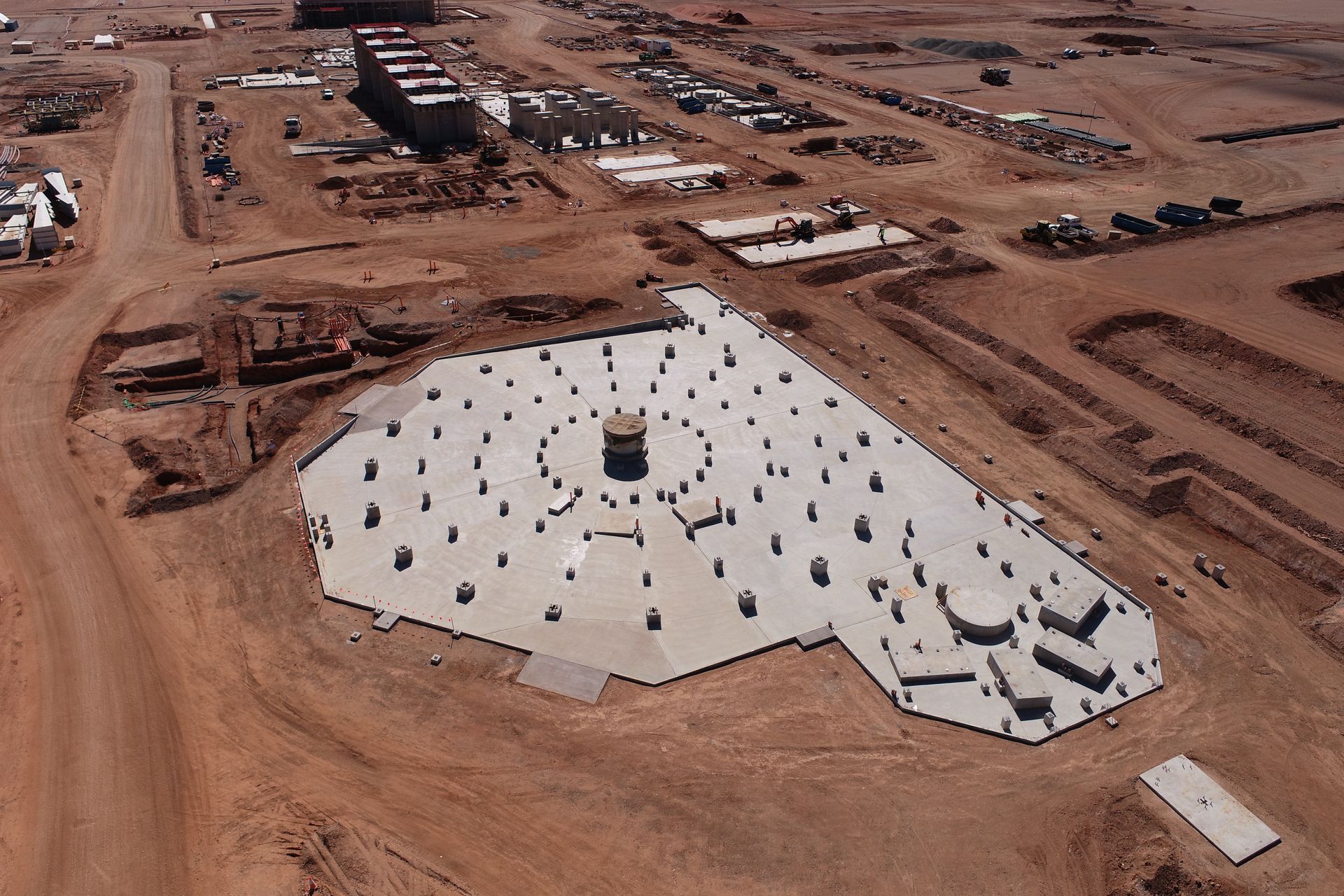 Man in striped sweater looking at a wall covered with papers and sketches.