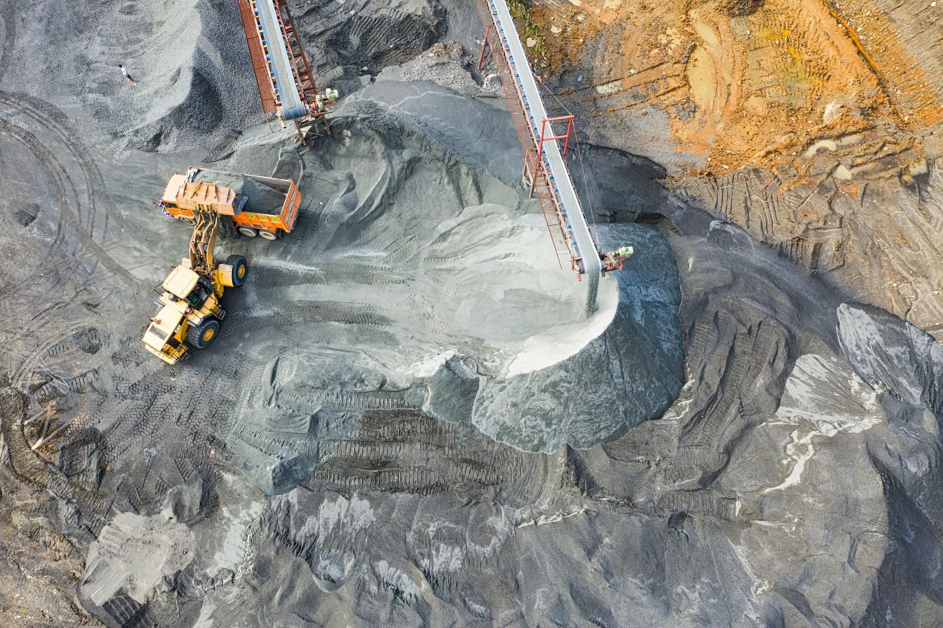 Aerial view of quarry; heavy machinery loading and processing gravel with conveyor belts.