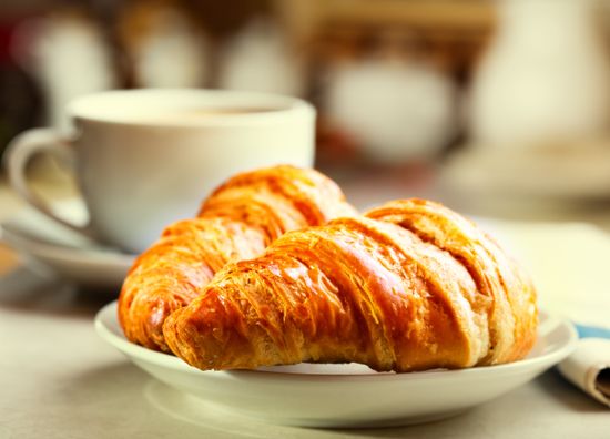 colazione con croissant, tazza di caffè nero e giornale
