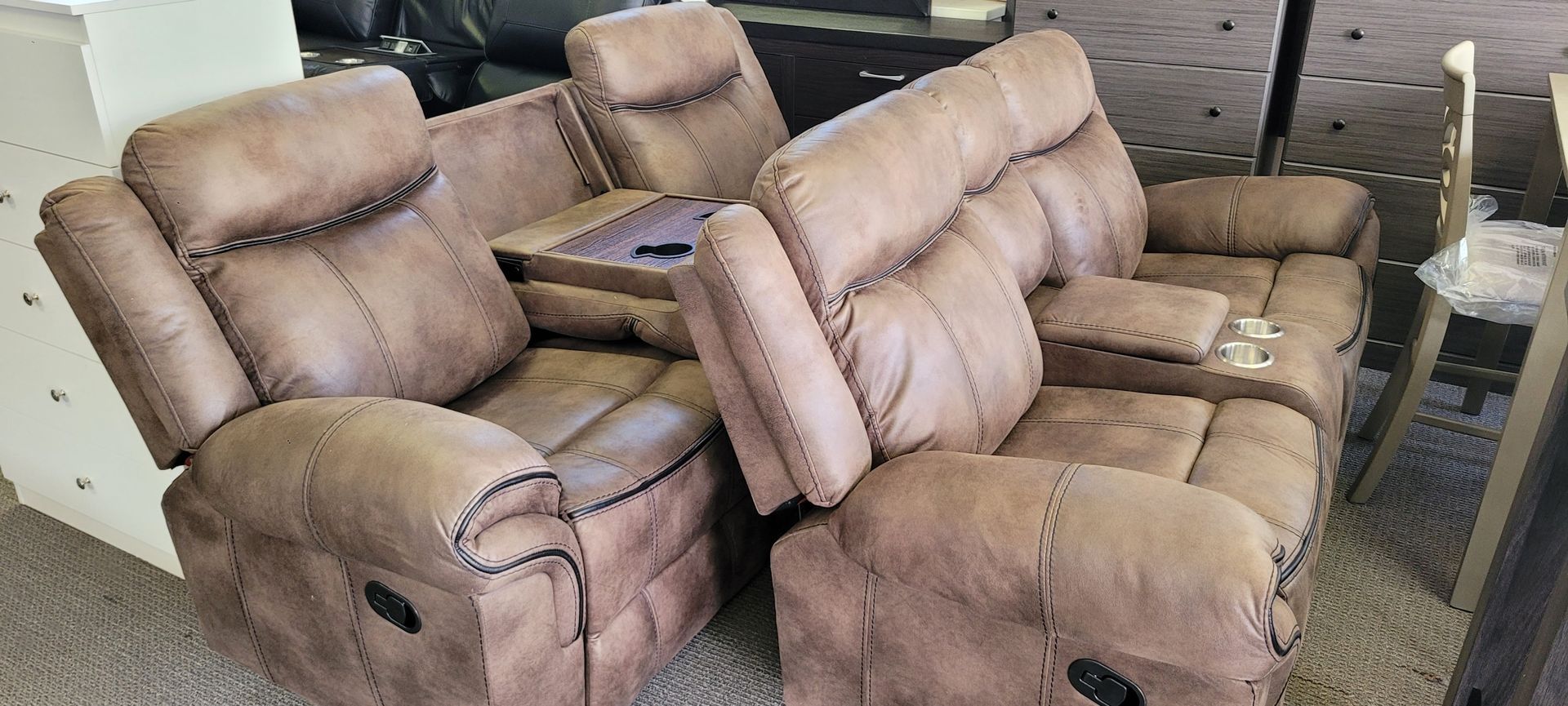 Brown reclining sofa with center console, in a store setting.