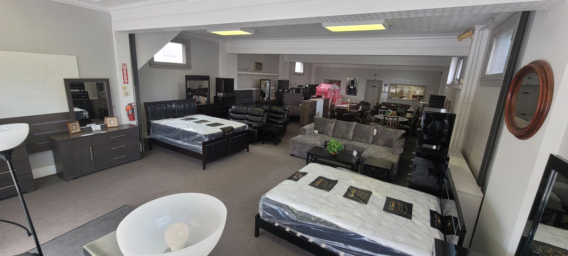 Furniture showroom interior with beds, sofas, and dressers on display.