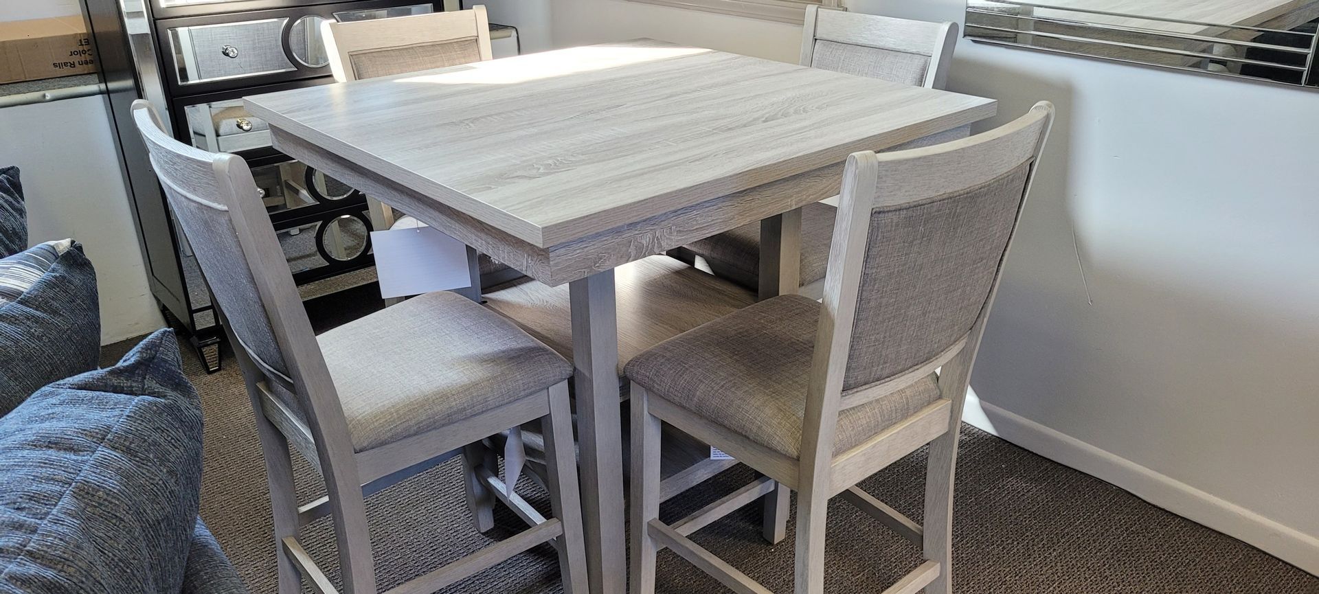 A square dining table with four matching bar stools in a room with a rug.