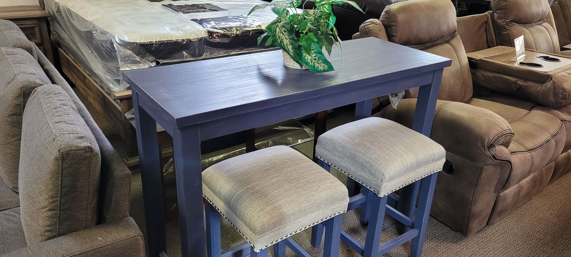 A dark blue table with two stools. Brown sofas are on either side. A plant sits on the table.