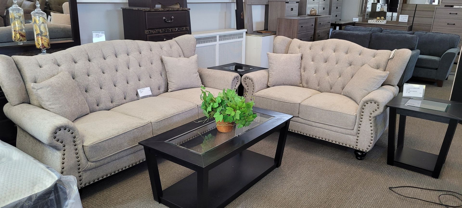 Beige tufted sofa set with a coffee table and side tables in a furniture store.