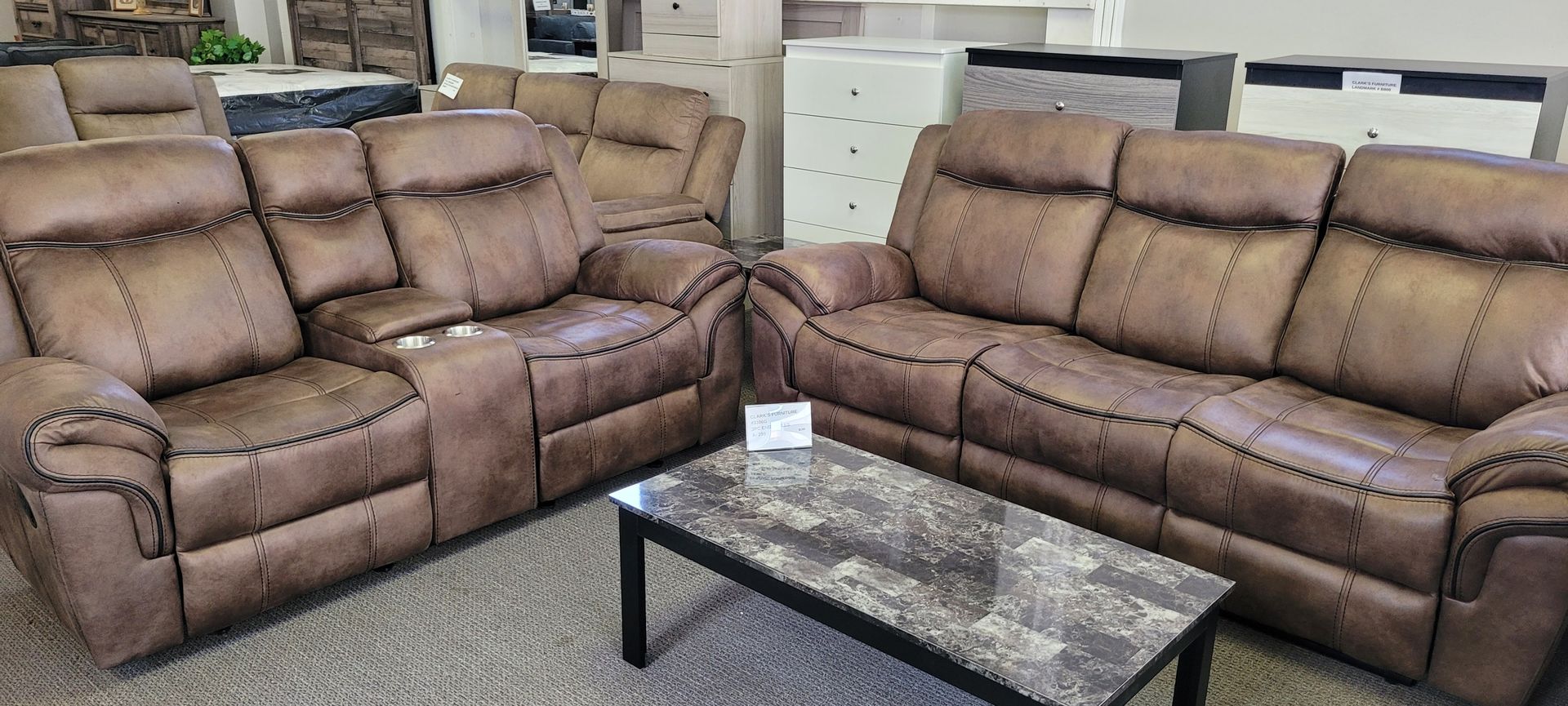Living room furniture set with brown leather couches and a marble-top coffee table.