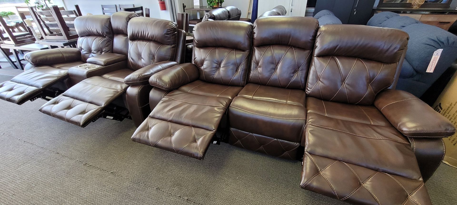 A brown leather recliner sectional with footrests extended in a furniture store.