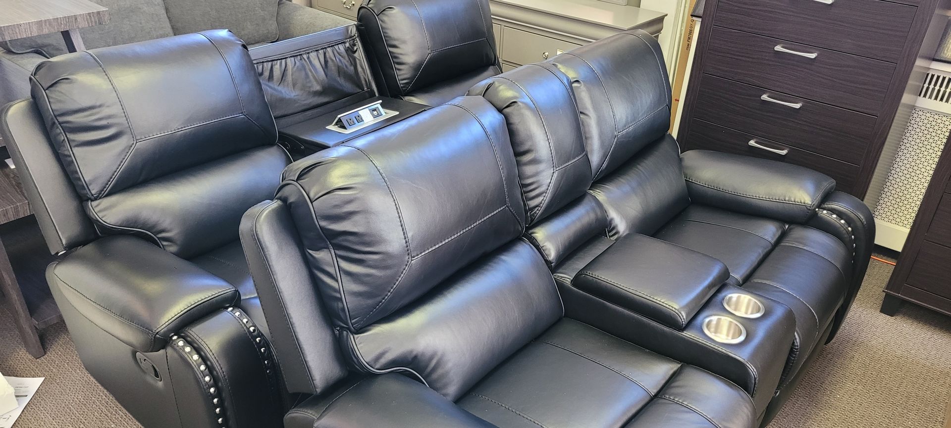 Black leather reclining sectional with cup holders and storage console.