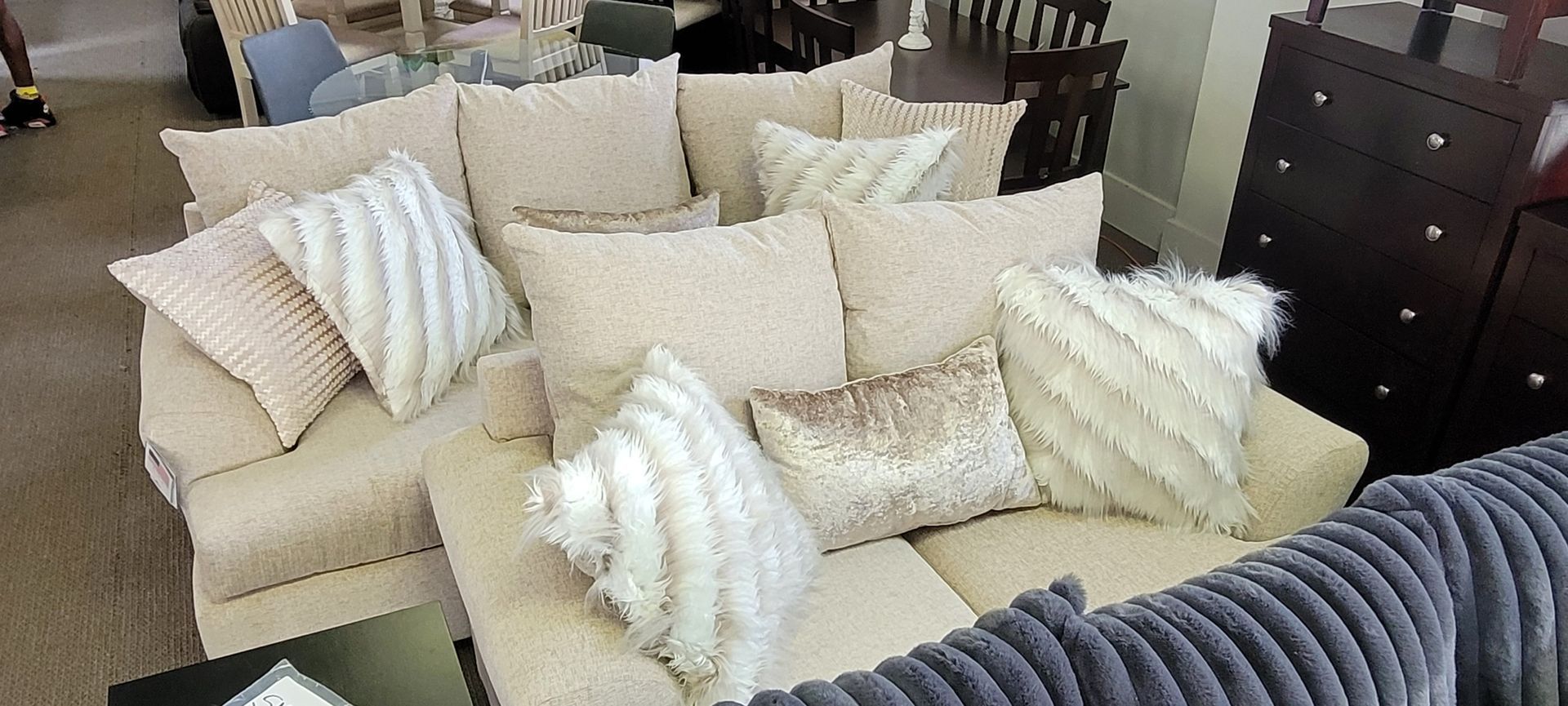 Beige sectional sofa with cream and white pillows, wooden furniture in the background.