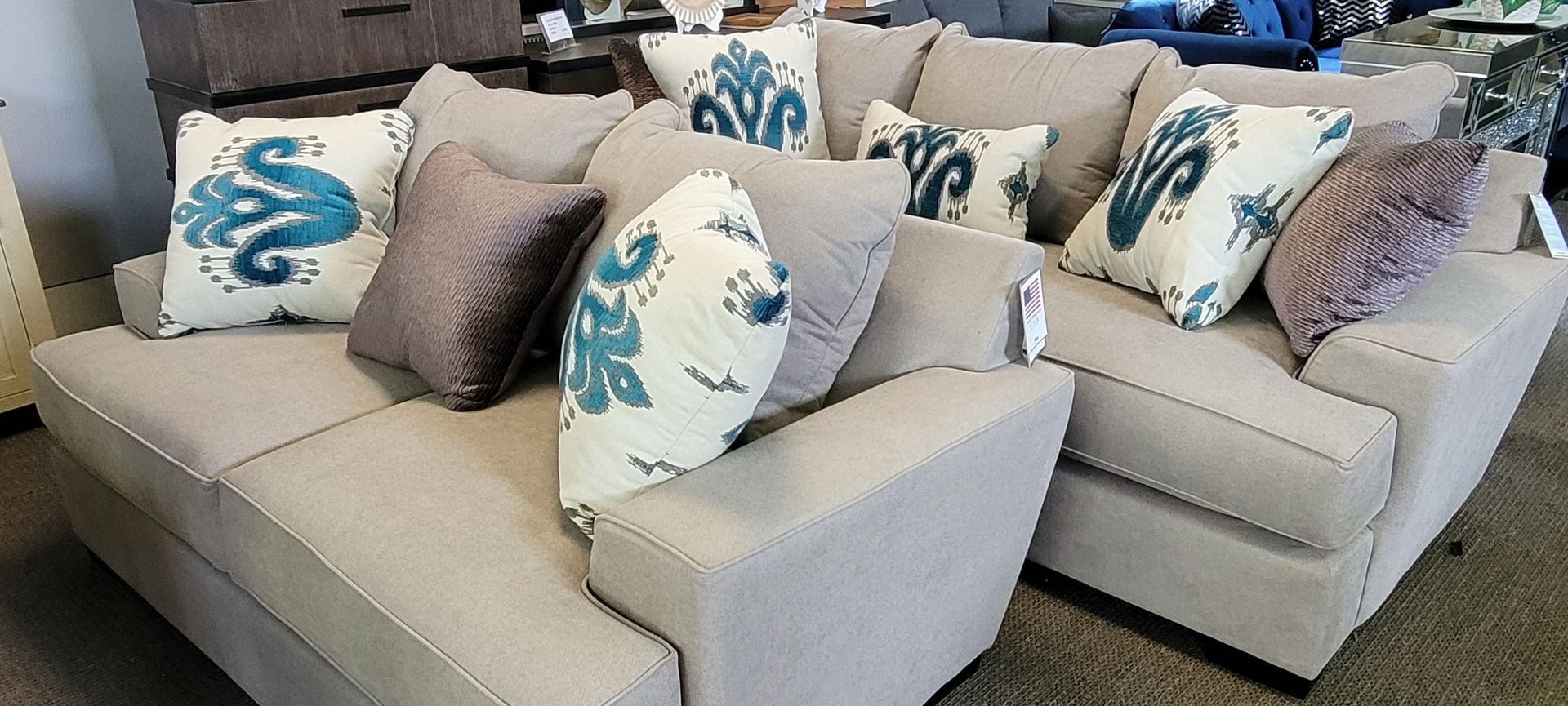 Beige sectional sofa with patterned throw pillows in a showroom.