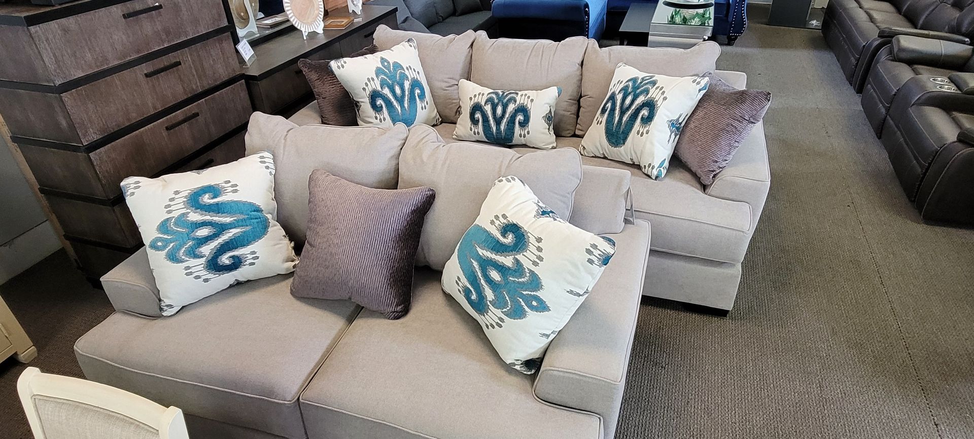 A light gray sectional sofa with decorative blue and gray pillows in a furniture store.