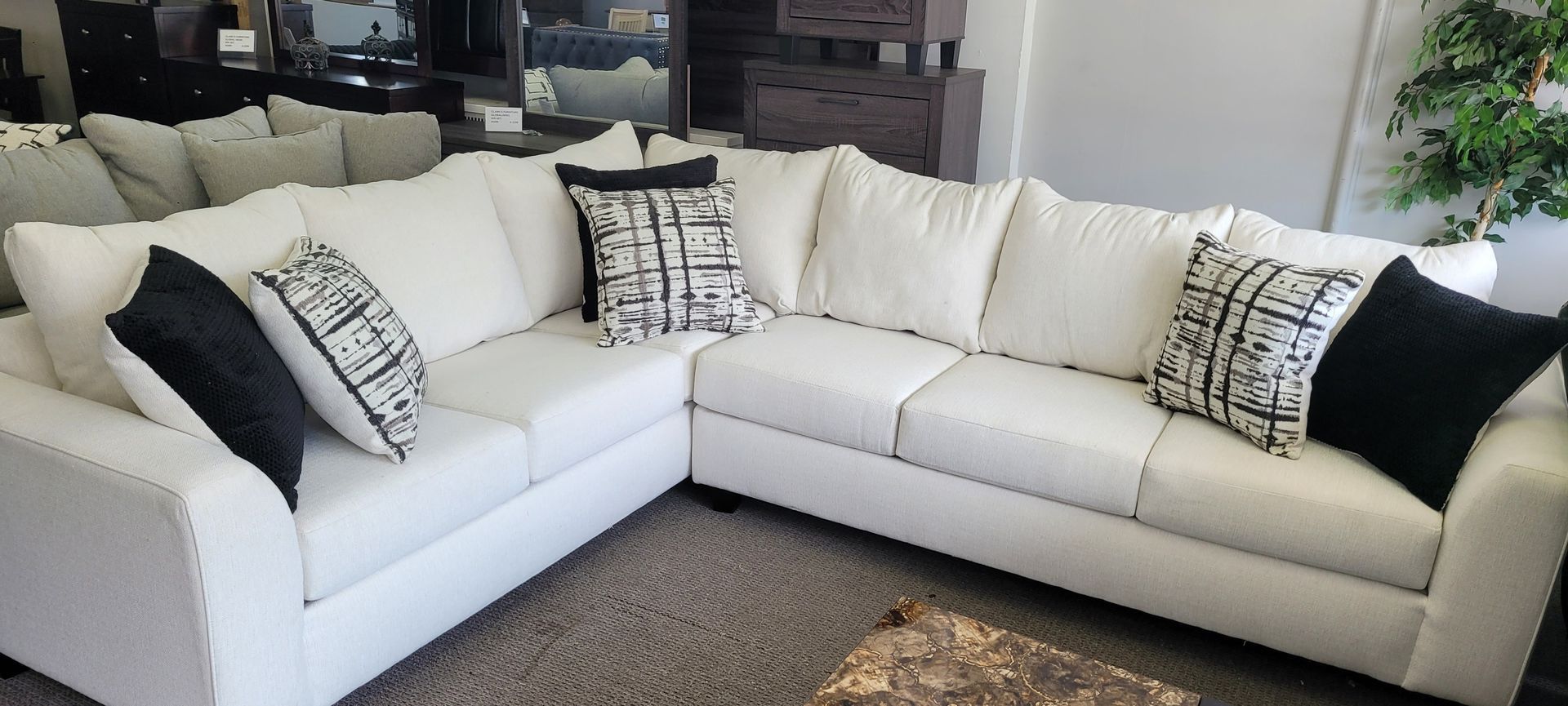White sectional sofa with black and white throw pillows in a furniture store.